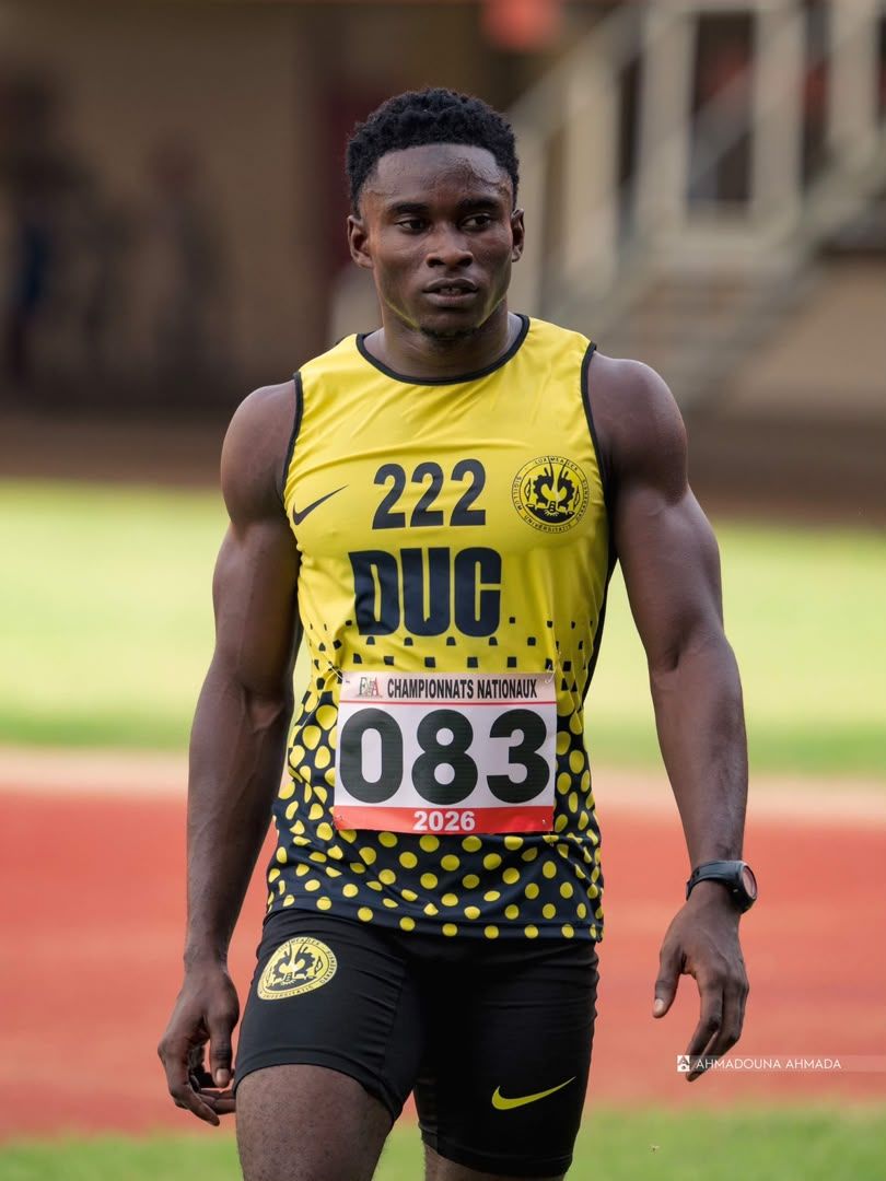 Sprinter in a yellow vest smiling on the track